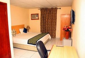 伊凯贾Room in Lodge - Eaglespark1960 Hotel的酒店客房配有一张床铺、一张桌子和一张书桌。