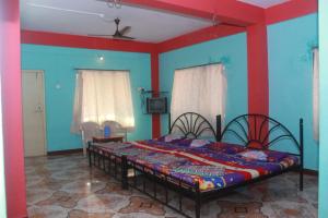 拉特纳吉里Vamoose Yashwant Niwas的一间设有床铺的卧室,位于一间拥有蓝色墙壁的房间