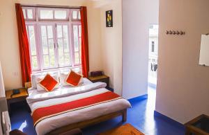 NamchiDungmali Heritage Resort的客房配有带橙色枕头的床和窗户。