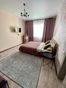 苏尔古特Уютная квартира на Ауре的一间卧室配有一张床、一把椅子和地毯