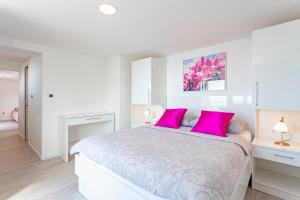 布雷拉Villa King Apartments的白色卧室配有带粉红色枕头的大床