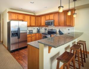 奇兰世誉奇兰公寓式酒店 - 湖苑的厨房配有木制橱柜和不锈钢冰箱。