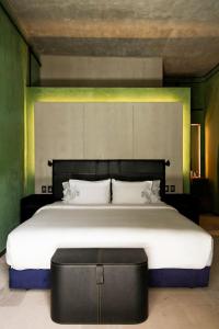 瓦哈卡市Pug Seal Oaxaca的一间卧室配有一张大床和一张黑色的搁脚凳