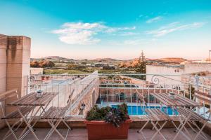 Santa LuċijaSweet Life Gozo的阳台配有椅子,享有游泳池的景色
