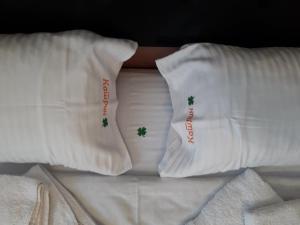 兹拉蒂博尔Apartment Katrin的床上的2个白色枕头,上面有绿色的十字架
