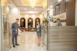 宁平MOMALI Hotel Ninh Binh的男人和女人在商店里摇手