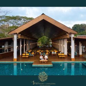 布莱尔港Symphony Samudra Beachside Jungle Resort And Spa的两人坐在游泳池旁的亭子