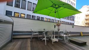 美因河畔法兰克福克里斯托尔法兰克福市酒店的阳台配有带绿伞的桌椅