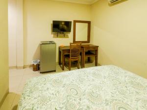 雅加达Rhiz Guest House Tebet的一间卧室配有一张床、一张桌子和一台电视