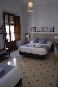 格拉纳达La Perla Granada Suites的一间卧室配有两张带蓝色枕头的床