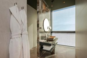 利马索尔ONLY Boutique Suites & Residences的一间设有白色长袍和窗户的浴室