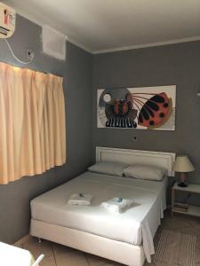 帕尔马斯Hotel Graciosa Palace的卧室配有一张床铺,墙上挂着一幅 ⁇ 虫照片
