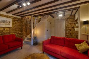 Fab 2 Bed Cotswolds Cottage with Private Courtyard的客厅设有红色的沙发和石墙