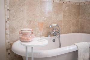 凯特尔韦尔The Cottage Tea Room B&B的浴室提供一瓶香槟和一张桌子上的玻璃杯