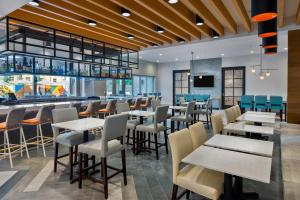 坦帕Hyatt House Tampa Airport/Westshore的一间带桌椅的餐厅和一间酒吧