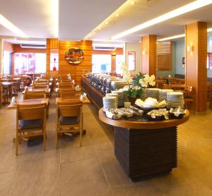 卡波布里奥Malibu Palace Hotel的餐厅设有桌椅和盘子