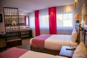 莫雷利亚阿拉米达历史中心酒店的酒店客房,设有两张床和红色窗帘