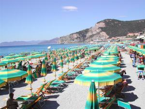菲纳莱利古雷卡萨维肯兹伊索费拉酒店的海滩上摆放着许多绿黄伞