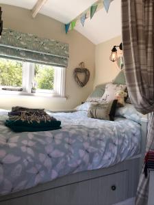 利明顿Shepherds Hut with Hot Tub的一间卧室配有一张带紫色棉被的床和窗户。