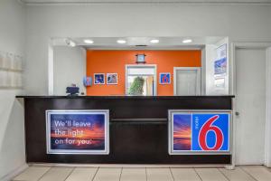 阿梅里克斯Motel 6-Americus, GA的带有橙色墙壁和标志的等候区