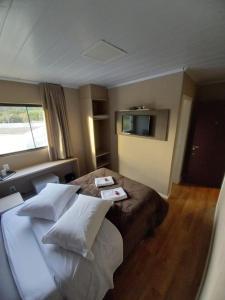 邦雅尔丁-达塞拉Pousada Rota12的酒店客房配有带枕头的床和电视。