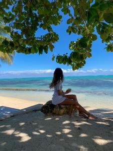 莫雷阿Moorea Island Beach Hotel的坐在海滩上岩石上的女人