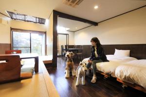 下田Welcome Inn SunnySteps的和两只狗一起坐在床上的女人