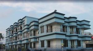 曼达莫尼Arya Beach resort的蓝色的建筑,旁边设有阳台