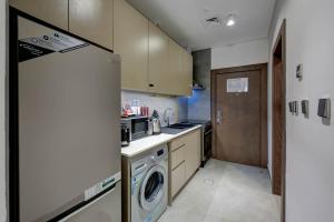 迪拜ABAR HOTEL APARTMENTS DIP-1的厨房配有冰箱、洗衣机和烘干机