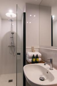巴黎Hôtel Le Milie Rose的浴室配有盥洗盆、淋浴和毛巾