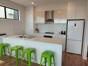 波塔灵顿Waterline Property Portarlington的厨房配有厨房柜台的绿色凳子