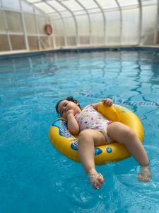 托里什韦德拉什Dii Beach House - Casa de Férias com piscina interior aquecida的一个小女孩躺在游泳池里的木筏上
