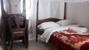MoyoNasera Suites Hotel的一间卧室配有一张带椅子和床罩的床