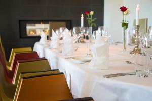 厄什塔Havila Hotel Ivar Aasen的一张长桌,配有白色的桌子和椅子及蜡烛