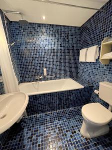 温特斯韦克Hotel restaurant Stad Munster的蓝色瓷砖浴室设有浴缸和卫生间