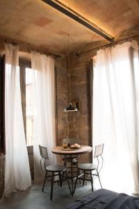 卡尔多纳Casa Boutique nº 24的配有白色窗帘的客房内的桌椅