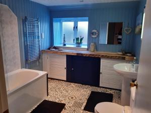 KirkcowanCraighlaw Arms Boutique B&B的浴室配有蓝色的墙壁、浴缸和水槽。