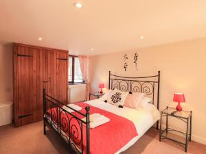 WigtonHorseshoe Cottage的一间卧室配有一张大床和红色的床罩