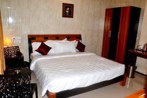 钦奈Peace Inn Chennai的一间卧室配有带白色床单和红色枕头的床。