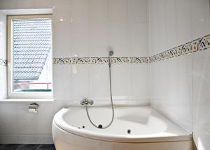 帕兰加Žalias namas的带窗户的浴室内的白色浴缸