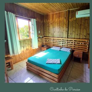 甘博阿Cantinho do paraíso的木制客房内的一间卧室,配有一张床