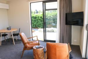 特卡波湖Fivestone Suite的客厅配有电视、椅子和桌子
