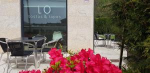 欧德鲁佐LO旅馆的桌子、椅子和粉红色的鲜花在建筑前