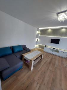 托伦Nowoczesny apartament w zacisznym sercu Torunia.的客厅配有蓝色的沙发和桌子
