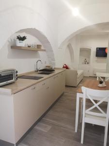 贝瓦尼亚Dimora San Francesco的厨房配有白色橱柜、桌子和沙发