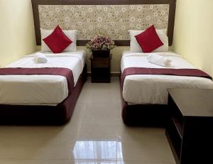 ChemorSun Inns Hotel Meru Raya的两张位于酒店客房的床铺,配有红色枕头