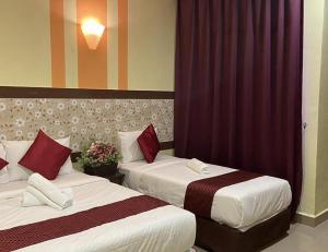 ChemorSun Inns Hotel Meru Raya的配有红色窗帘的酒店客房的两张床