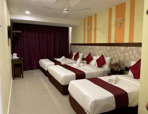 ChemorSun Inns Hotel Meru Raya的酒店客房,配有3张带红色枕头的床