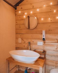 塔比奥Glamping rio frio Tabio的木墙上设有白色水槽的浴室