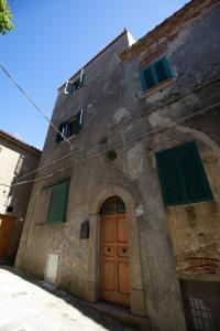 Isola del GiglioCasaMatta2的一座石头建筑,设有绿色百叶窗和门